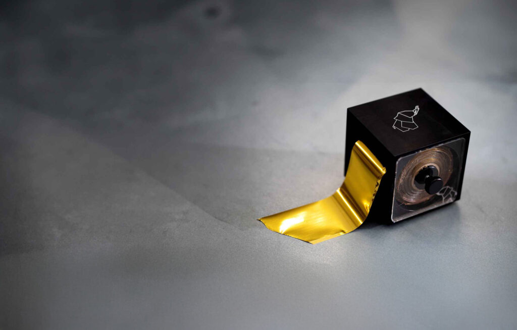 Close up of a small gold foil dispenser with the Metallic Elephant logo on it