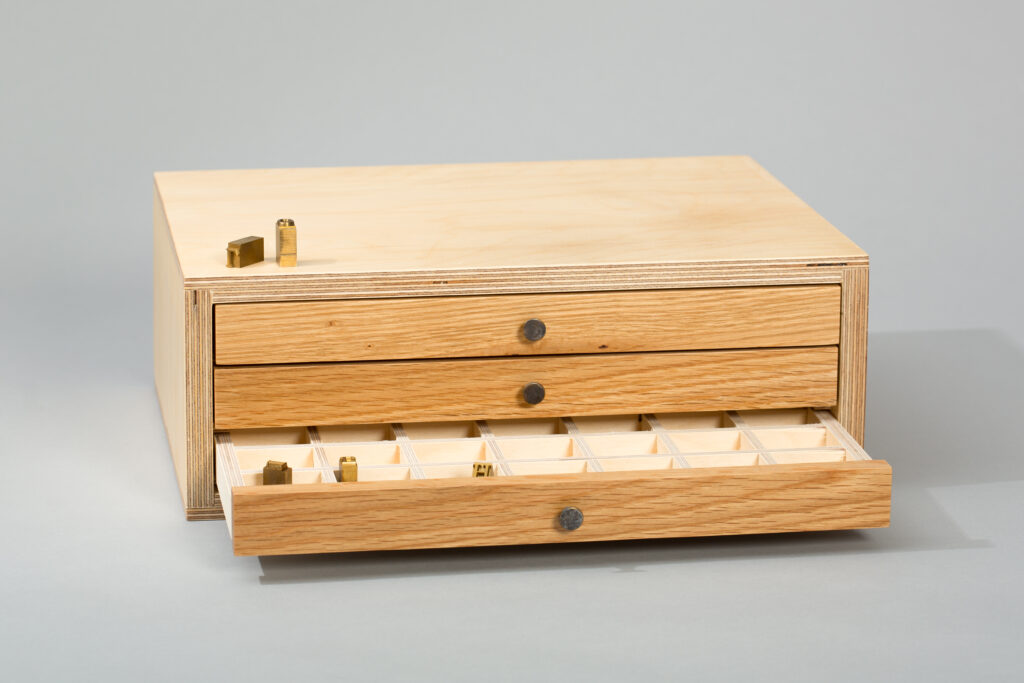 Wooden type cabinet with brass type letters in the drawers