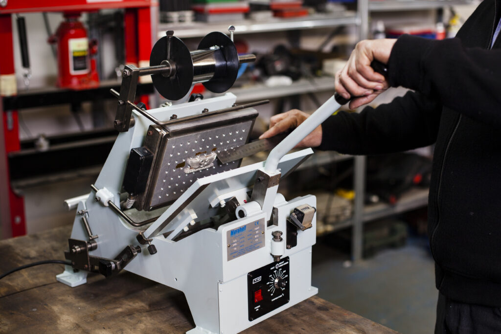 A man operating a marshall press machine