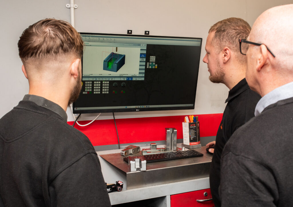 3 men operating a CNC machine computer