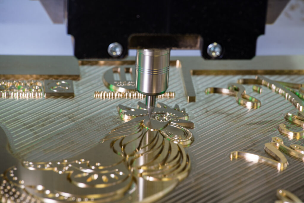 Close up of a CNC machine cutting out a branded brass die